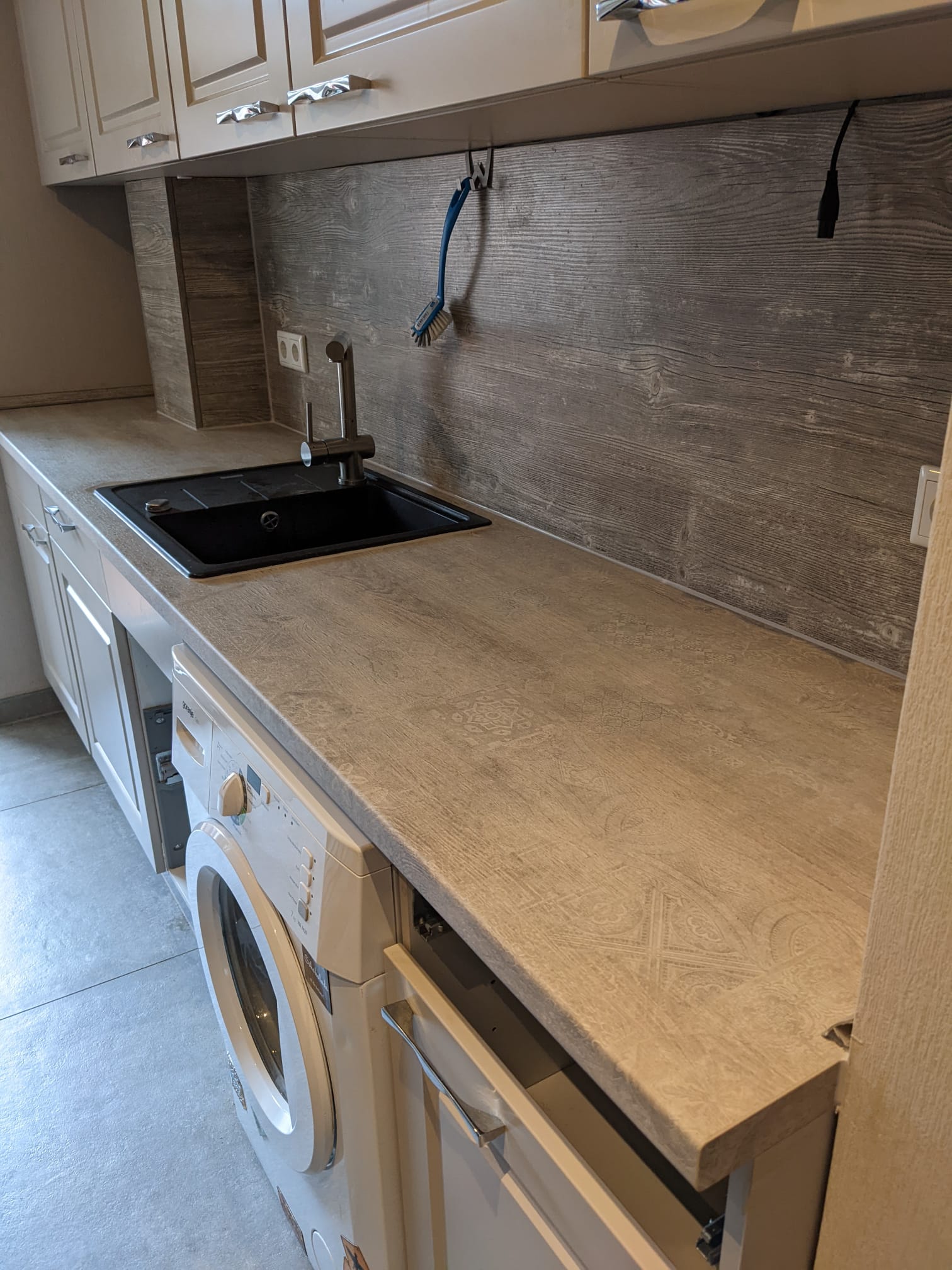 Foto einer neuen Küche, Küchenaufbau, helles Holz, eingebaute Waschmaschine und Spüle            
