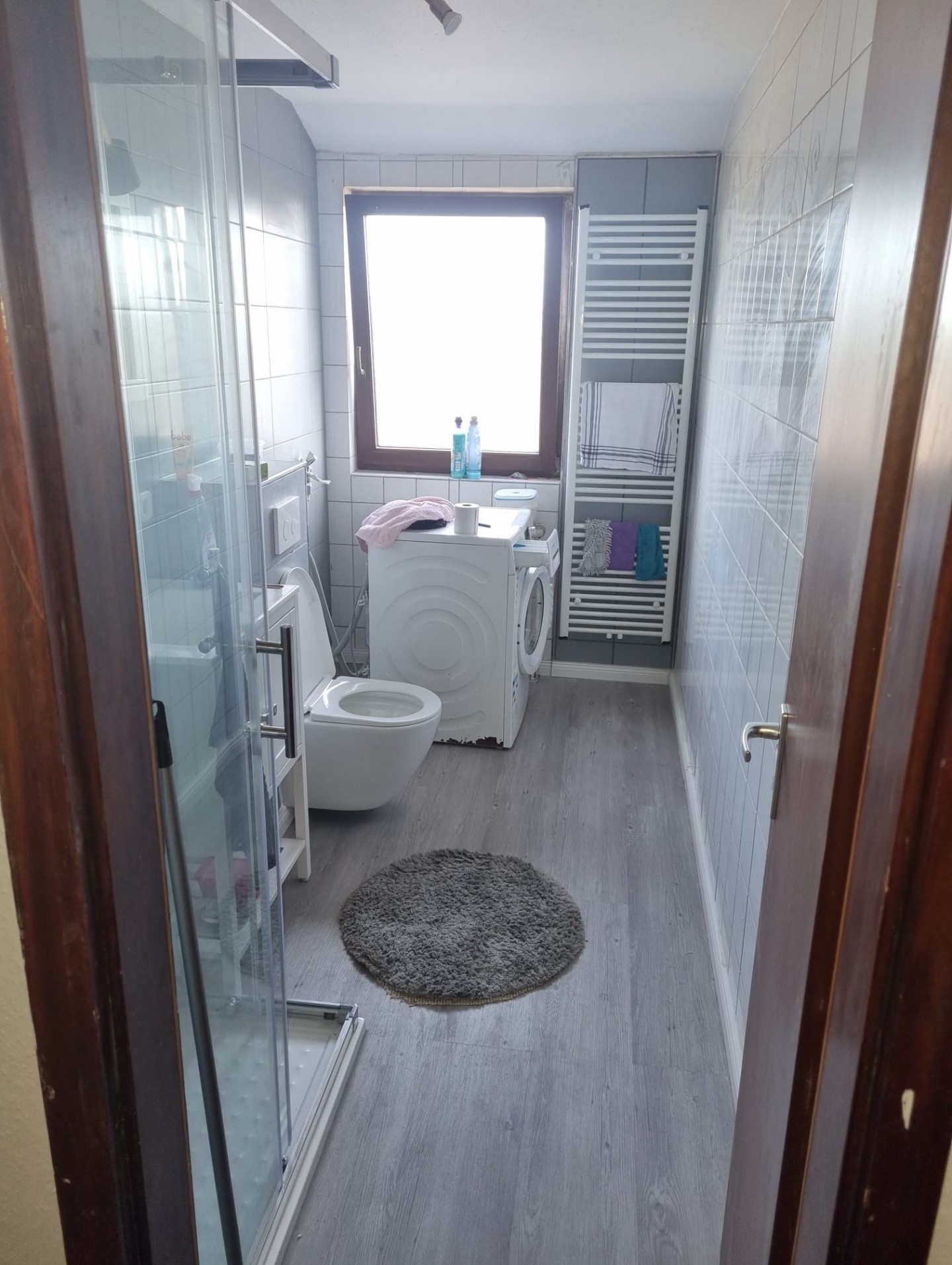 Foto eines sanierten Badezimmers, grauer Laminatboden, Dusche, WC